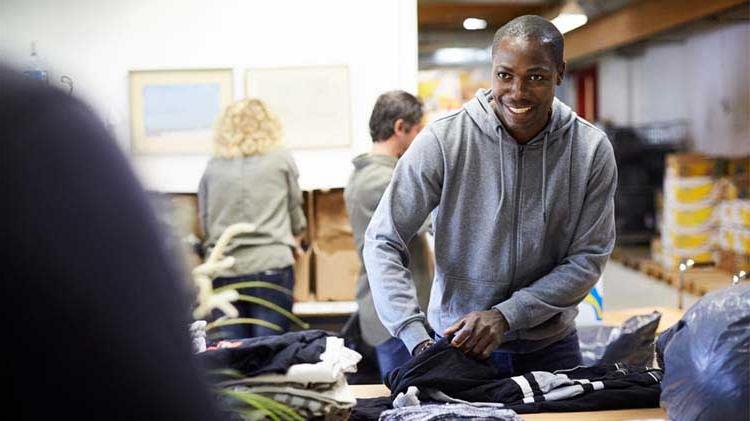 Man volunteering by packing clothes.