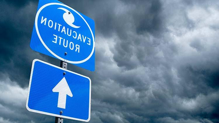 Hurricane evacuation route sign with storm clouds in the background.